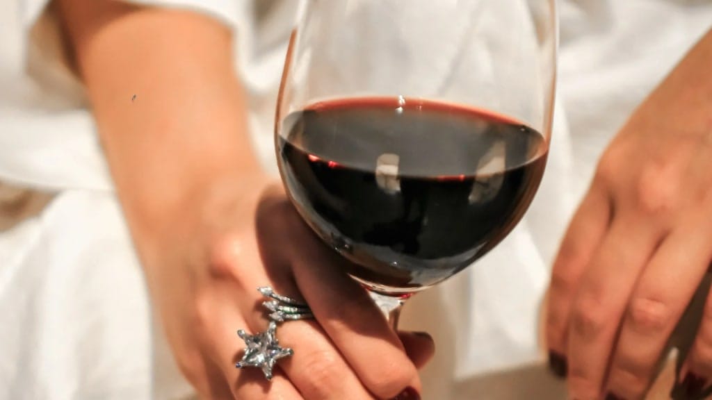 holding a glass of red wine