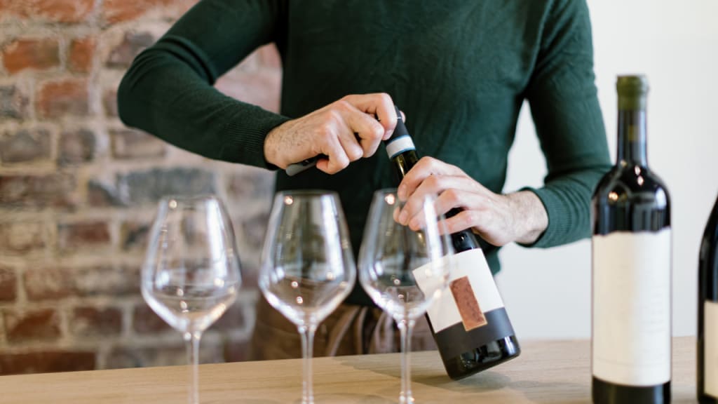 wine glasses and a man opening a bottle