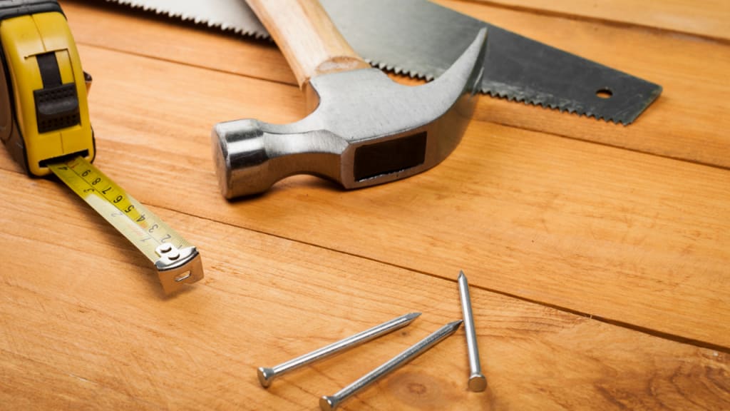 measuring tape, screws, and a hammer on a table