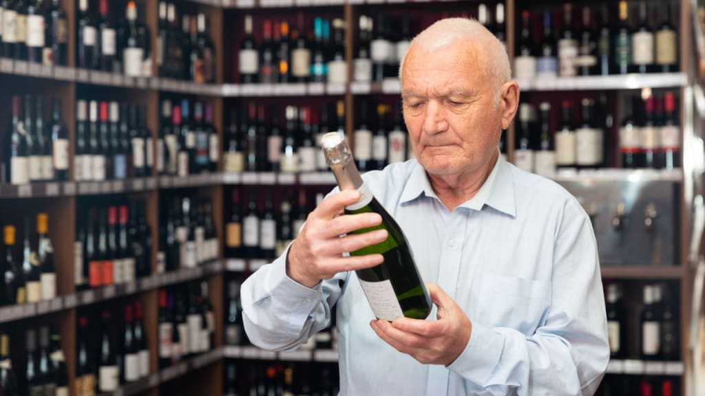 a man looking at a bottle of wine